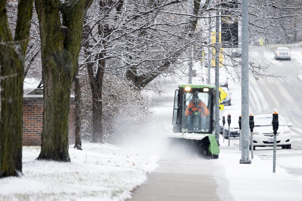 Snow plow removing snow from campus sidewalks