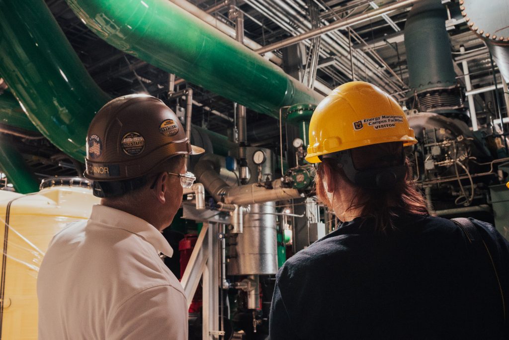 Two individuals with hard hats surveying underground piping