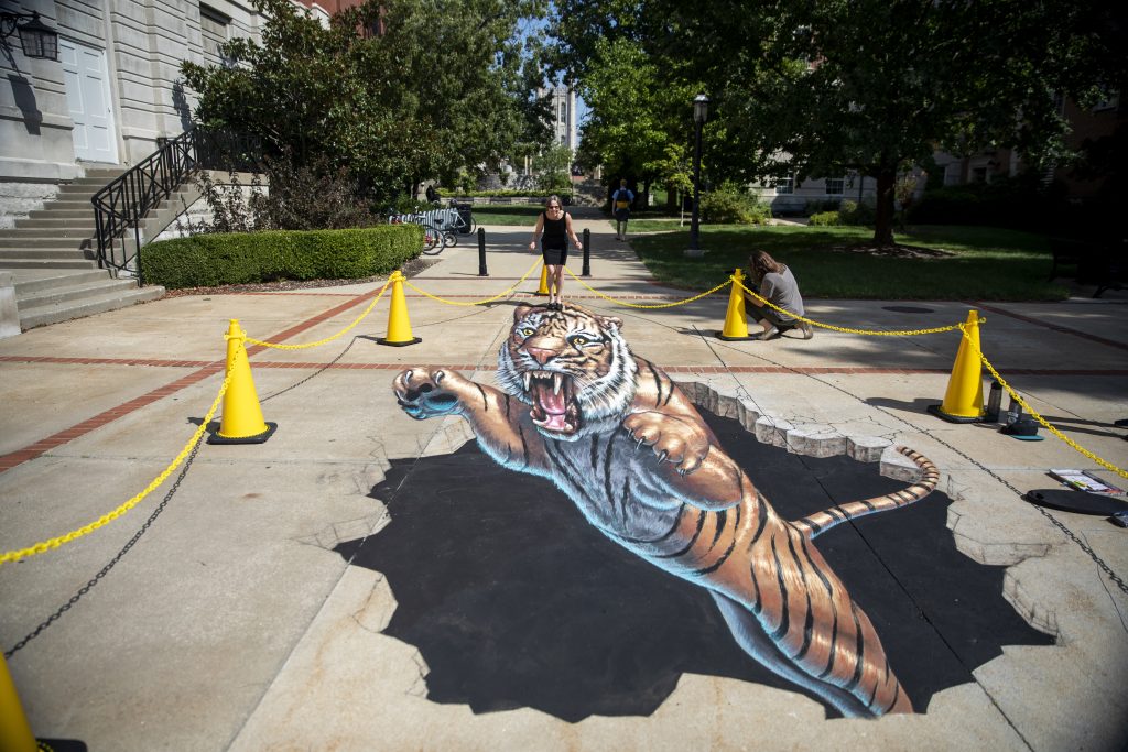 Sidewalk chalk drawing of a tiger coming out of the ground.