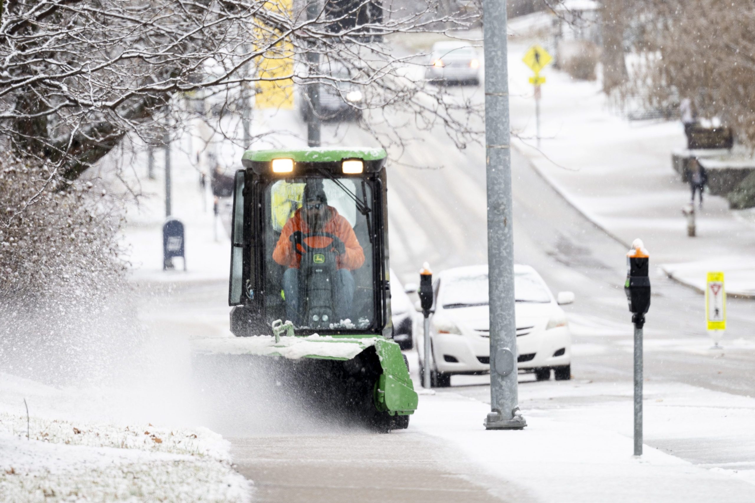 Landscape Services employee, Kamren, plowing snow from campus sidewalks